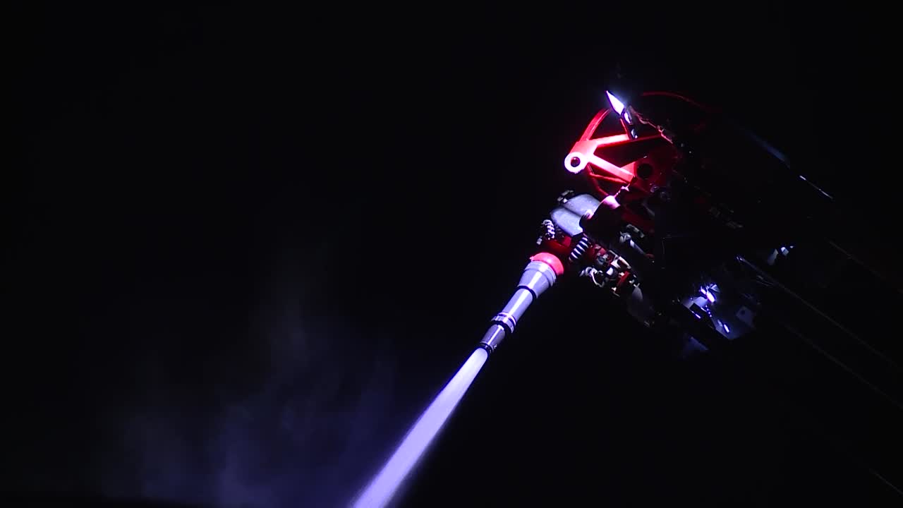 cañón de manguera contra incendios remoto rociando agua en llamas por la noche