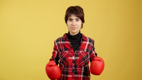 young woman in red boxing gloves posing against yellow background