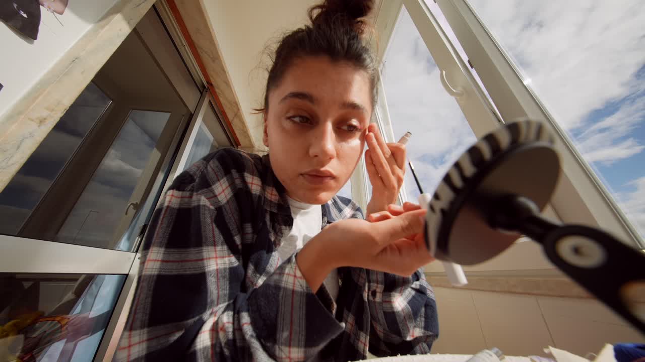 Giovane donna che applica l'eyeliner e parla per un vlog di bellezza