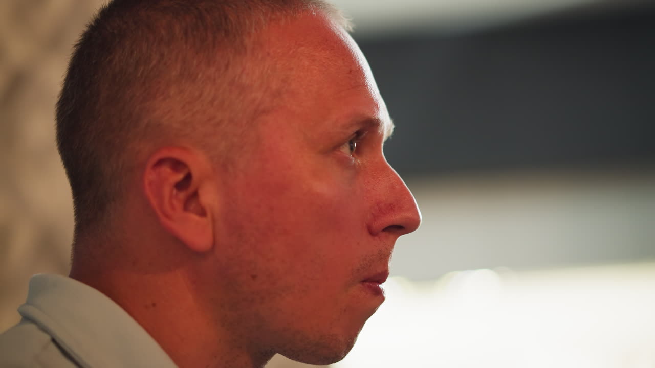 Close up side view of man eating meat brings hand close to mouth carefully checking for bone but finds none, with soft bokeh light shining warmly from background