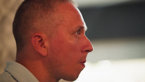 close up side view of man eating meat brings hand close to mouth carefully checking for bone but finds none, with soft bokeh light shining warmly from background