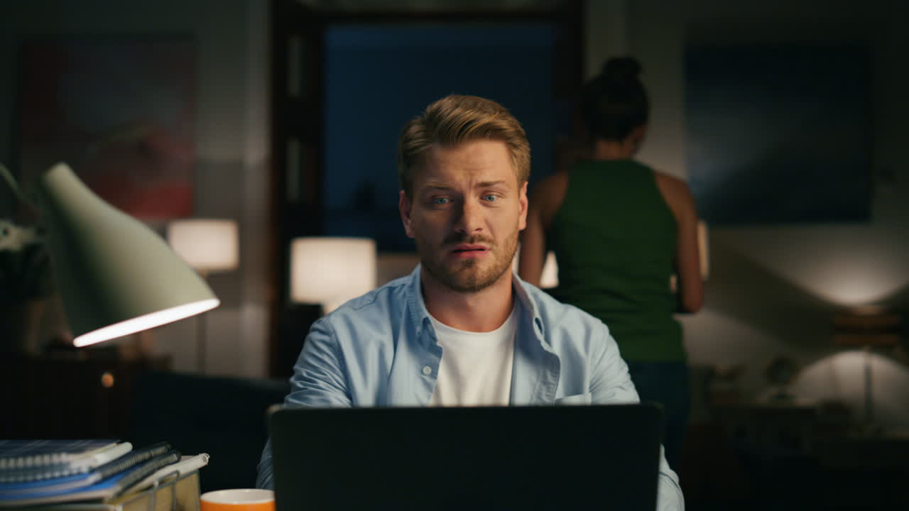 Bored woman disturbing man at dark interior. Guy driving away face mask wife