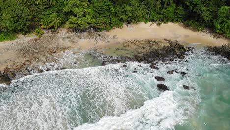 Costa-Rocosa-De-Agua-Turquesa-Y-Olas-En-Una-Playa-Tropical-Salvaje-Rodeada-De-Jungla-Verde-Y-árboles