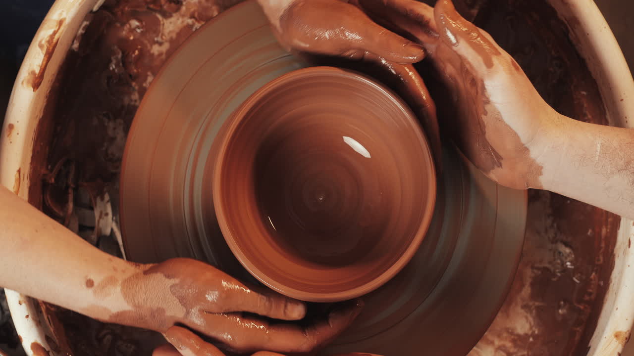 manos moldeando arcilla en una rueda de cerámica