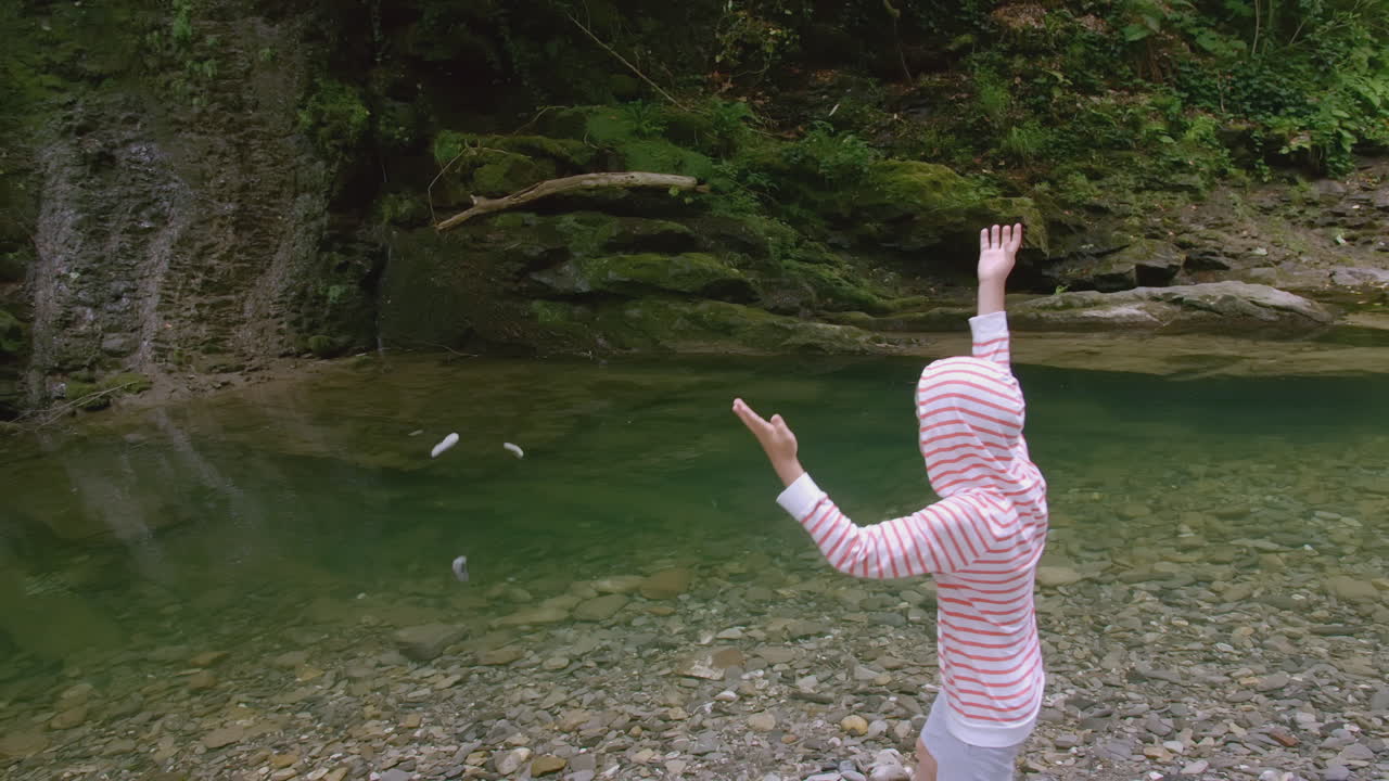 은 산의 하천에 돌을 던지는 아이