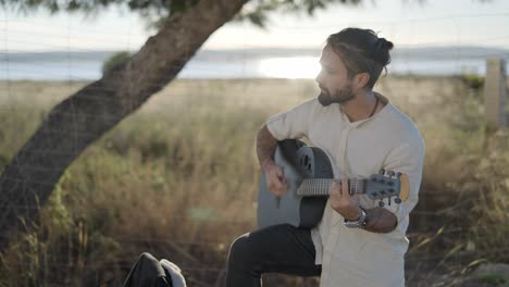 hombre tocando la guitarra acústica al aire libre