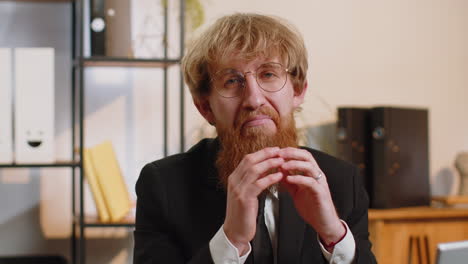 Confident-happy-redhead-businessman-in-glasses-looking-at-camera-with-smile-at-home-office-workplace