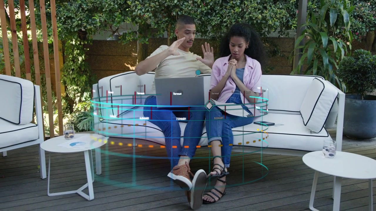 Man gesturing over laptop and woman tapping phone, manipulating AR interface for tech demo