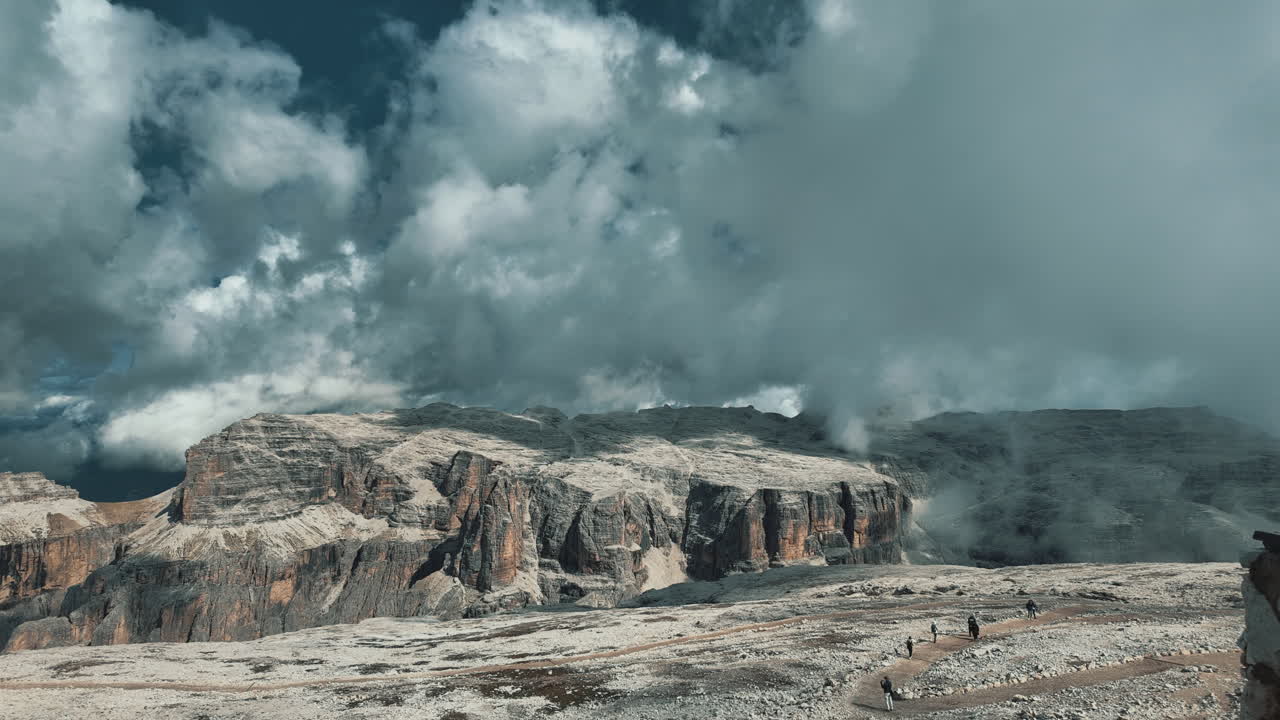 Dramatic timelapse capturing rolling clouds drifting over rocky Pordoi Pass landscape in Italian Dolomites, revealing dramatic mountain scenery and atmospheric cloudscape