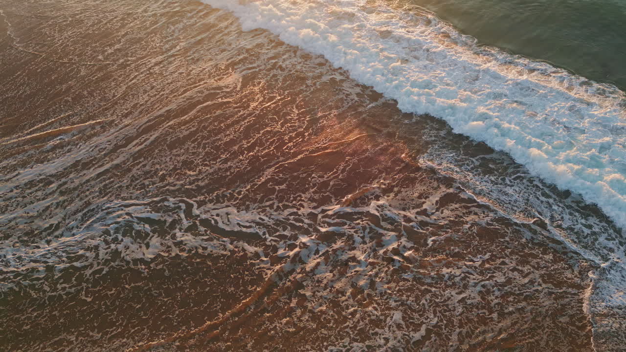 Drone view empty beach with stunning wild stormy ocean at soft sunset sunlight