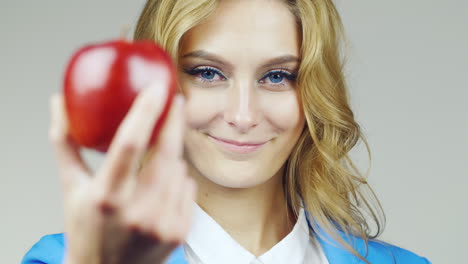 portrait of attractive blue-eyed woman with red apple focus switches smoothly from the face on the a