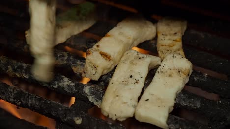 la mano derecha gira los dedos de queso halloumi en la fogata al aire libre por la noche