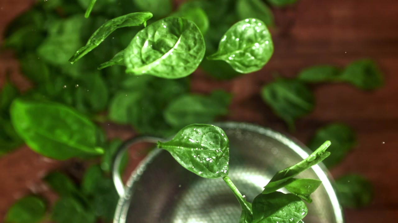 Foglie di spinaci freschi che vengono scosse in uno scolapasta al rallentatore