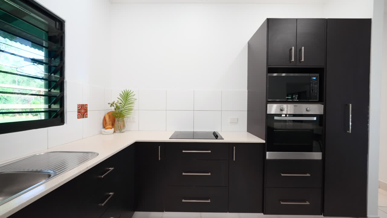 Luxury Elegant Tropical Home With Electric Stove Top and Sleek Modern Black Appliance and Cabinets On Large Rural property