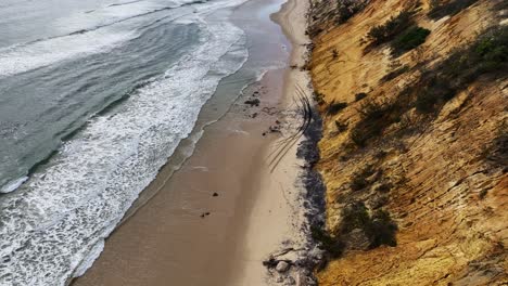 Fliegen-über-Den-Strand,-Während-Die-Flut-Fahrzeugspuren-Am-Fuße-Der-Sanddünen-Wegspült