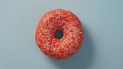 orange glazed donut rotating on blue, top view