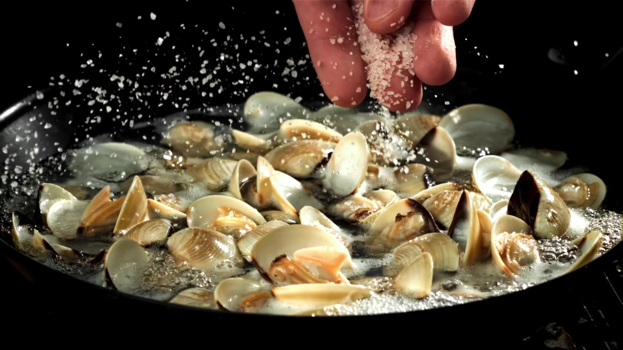 Chef Adding Salt to Fresh Clams Cooking in a Pan