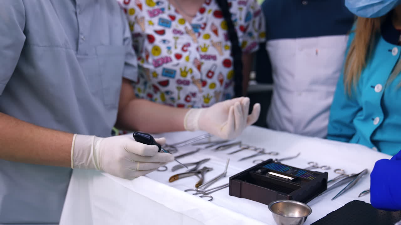 Gloved hands of a teacher holding a screwdriver and pulling the tiny screw. Dentistry students are taught at practice. Close up.
