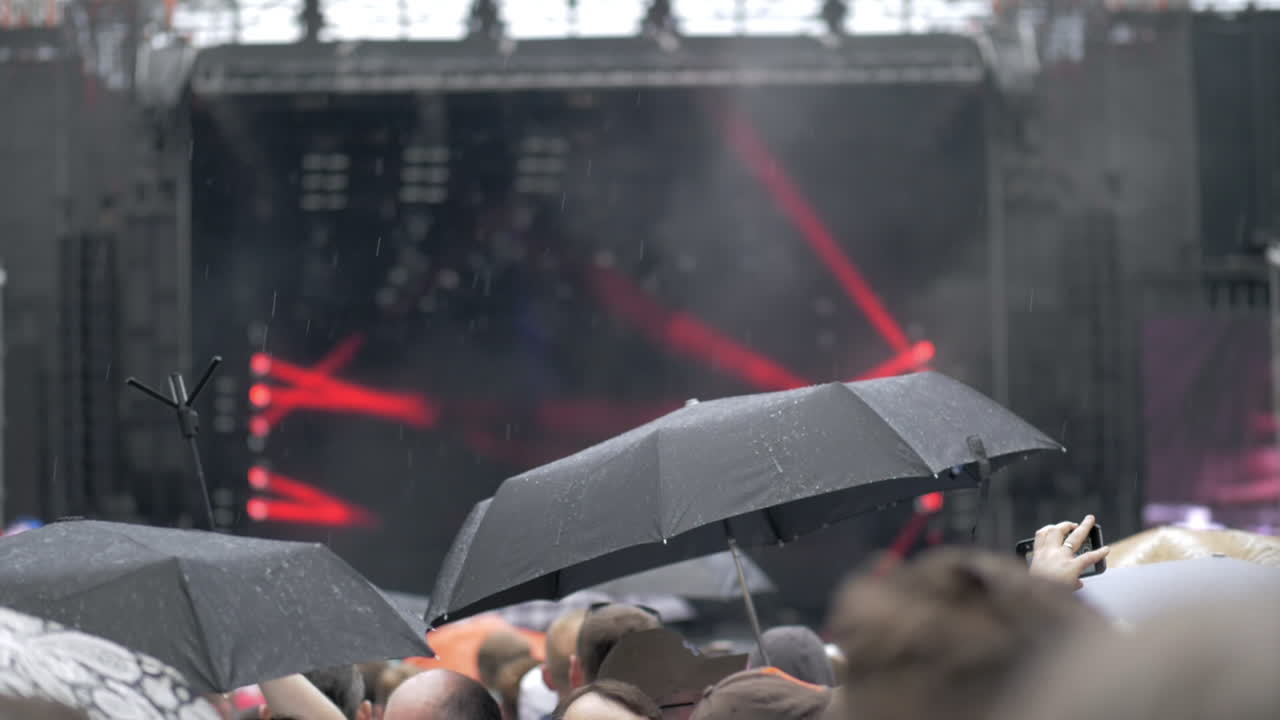 비가 내리는 야외 콘서트에서 사람들이