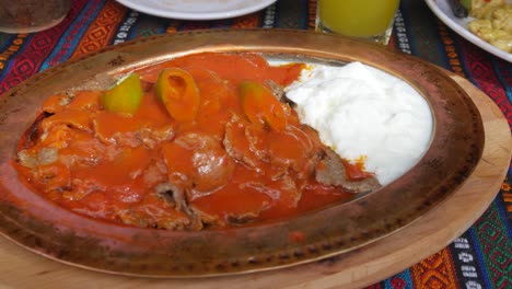comida tradicional turca a base de carne de tomate y pan árabe servida en una placa de metal de bronce