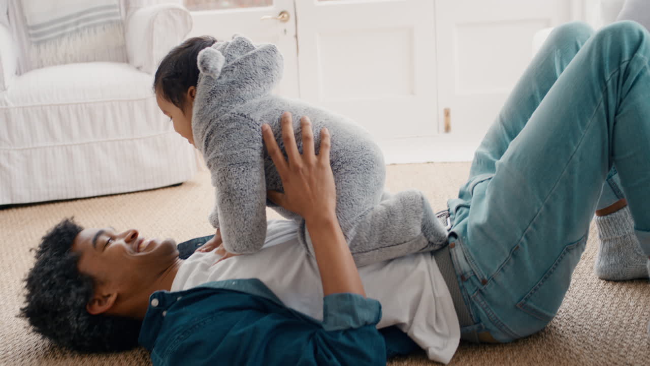padre felice che gioca con il bambino a casa giocoso che si diverte a tenere il bambino sorridente papà che si gode la paternità 4k