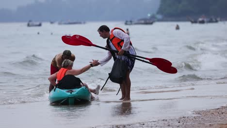 tourists receive assistance with kayak on the shore