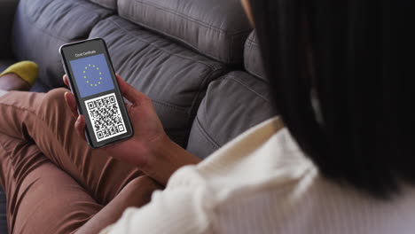 mujer en casa con un teléfono inteligente con certificado de vacunación contra la covid, bandera de la ue y código qr en la pantalla