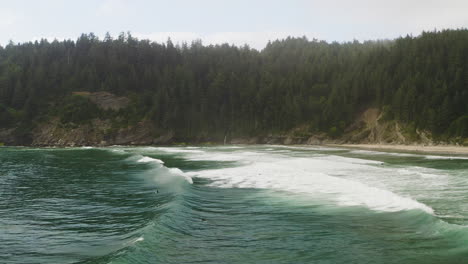 low flyover above surfers paddling through pacific ocean waves on oregon coast