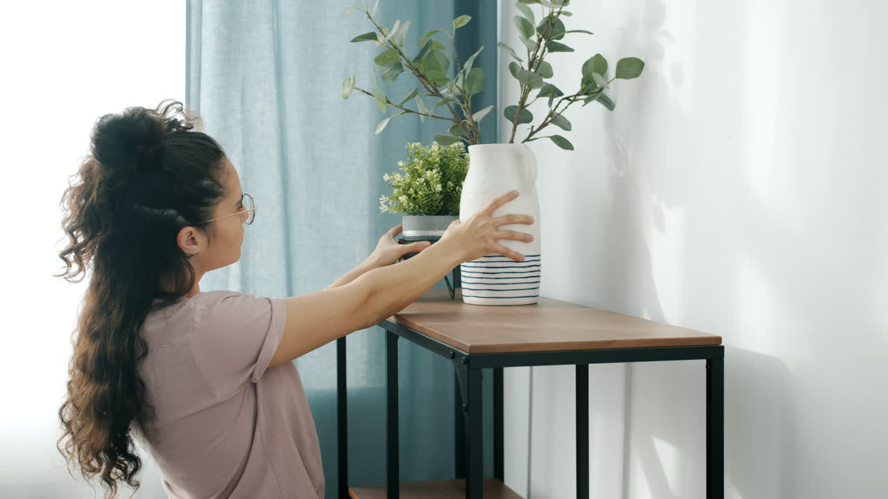 Woman Arranging Flowers on a Shelf