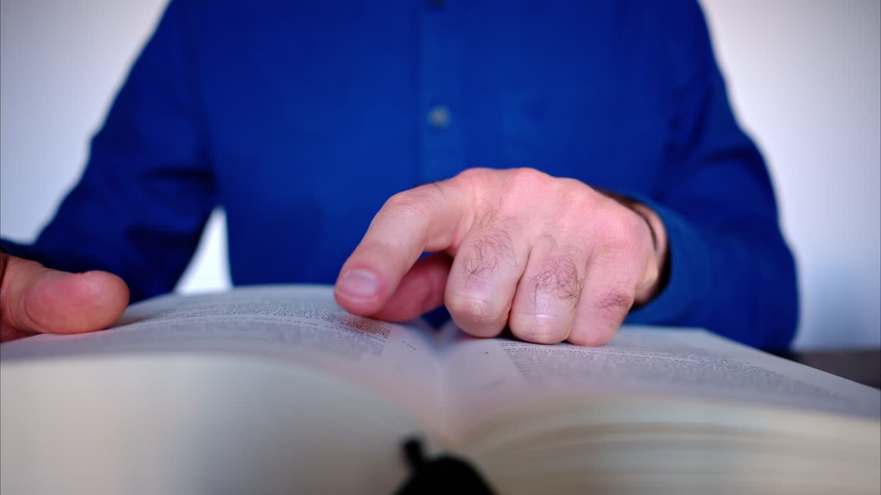 Close-up of a man reading a big book