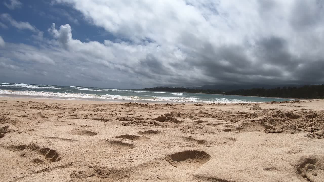lapso de tiempo desde la vista del piso de la arena y la playa y las nubes que se mueven rápidamente en una playa de la costa norte en oahu hawaii, que está desierta en este momento