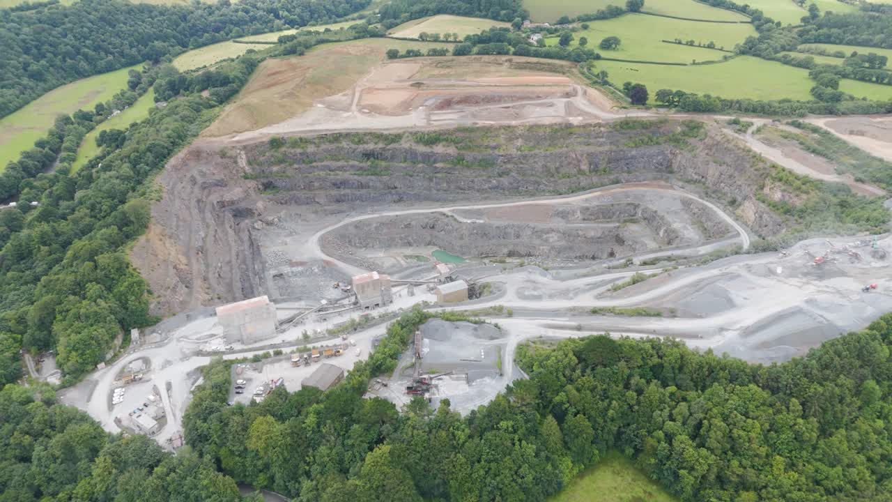 Aerial exterior of a vast aggregate mining operation set in the rural UK countryside, showcasing the extensive industrial site