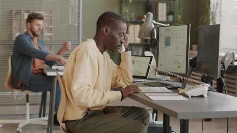 male trader talking on phone to clients in office