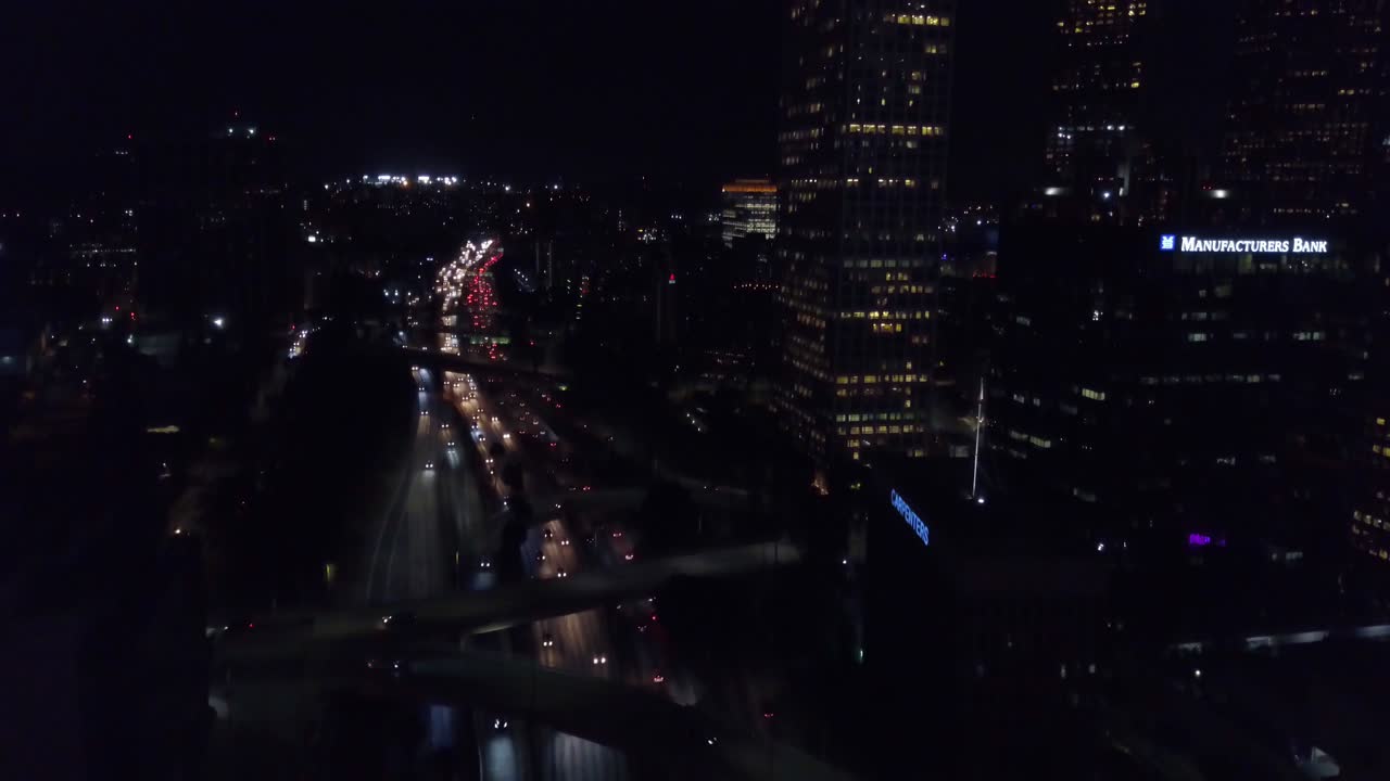 Aerial shot tilting up from freeway traffic to the Downtown Los Angeles skyline at night. 4K