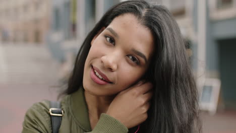 portrait of cheerful young mixed race woman on vacation removes earphones smiling happy at camera