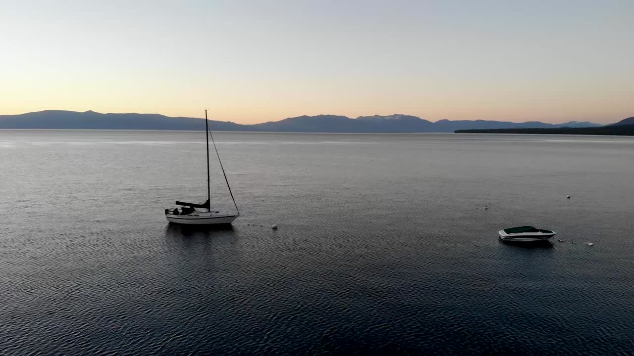 Ripresa drone che avanza mentre vola tra due barche su un lago dopo il tramonto