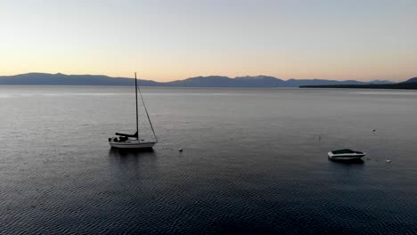 Drone-shot-sliding-forward-while-flying-in-between-two-boats-on-a-lake-after-sunset