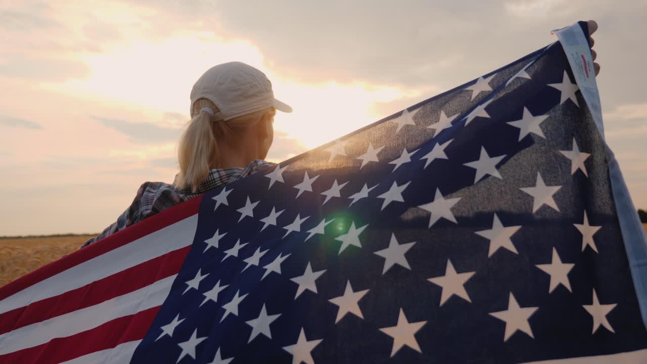 una agricultora con la bandera de estados unidos se encuentra en un campo de trigo maduro al atardecer concepto del día de la independencia