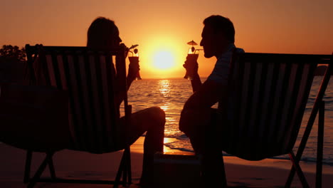 pareja bebiendo pareja durante la puesta de sol en la playa