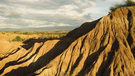 Aerial-flies-over-the-Tatacoa-Desert-during-Golden-Hour,-revealing-the-Landscape