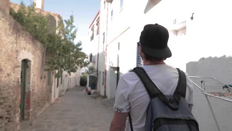 Slow-mo,-male-traveler-with-baseball-hat-and-backpack-walk-down-European-alleyway