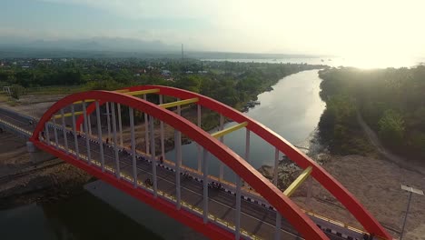 aerial footage of big highway bridge over a river with motorcycle parking and driving fast during sunset, samota bridge, sumbawa indonesia