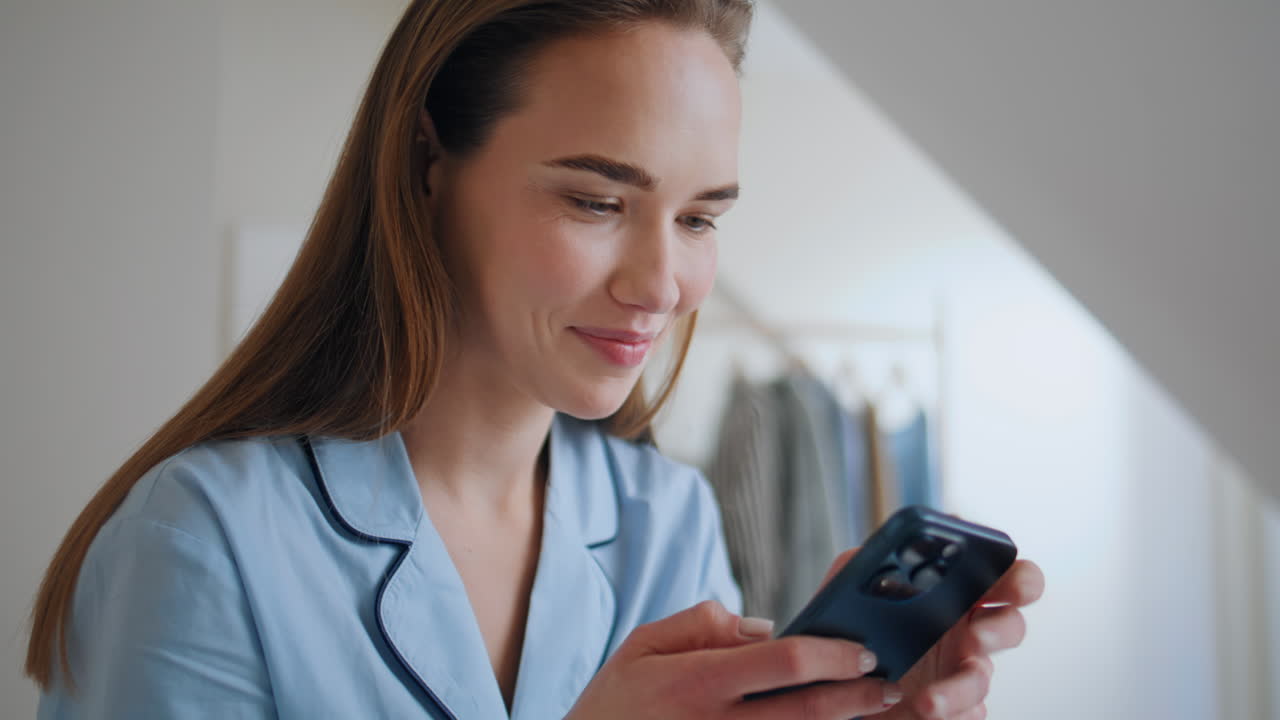 Joyful teenager typing smartphone in hotel bed closeup. Happy woman good news