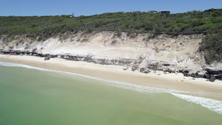 Bagnanti con veicoli parcheggiati sulla costa sabbiosa di Rainbow Beach a Cooloola, Queensland, con vista sul famoso Carlo Sand Blow in estate
