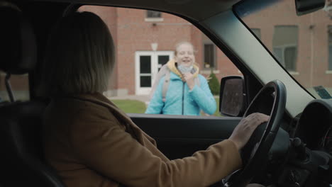 mom picks up her daughter from school, the child in the mask runs to the car. studying during the coronavirus epidemic