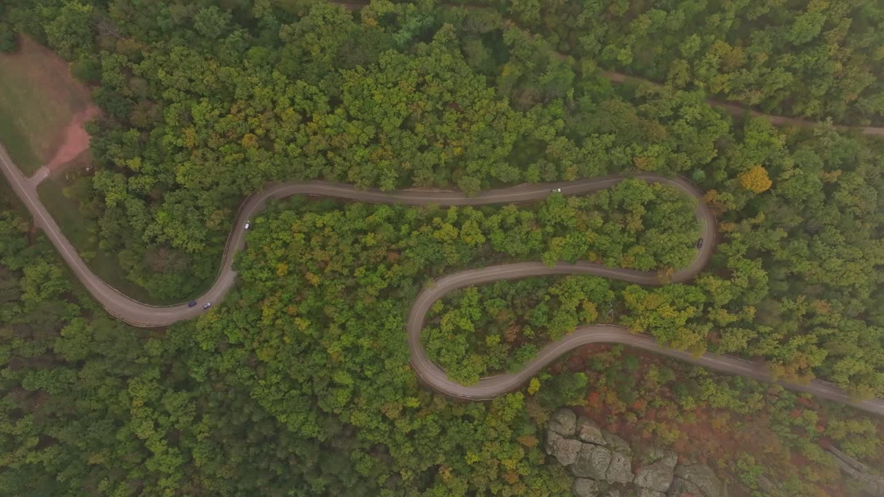Aerial shot of traffic weaving through fall forest hues, Bulgaria