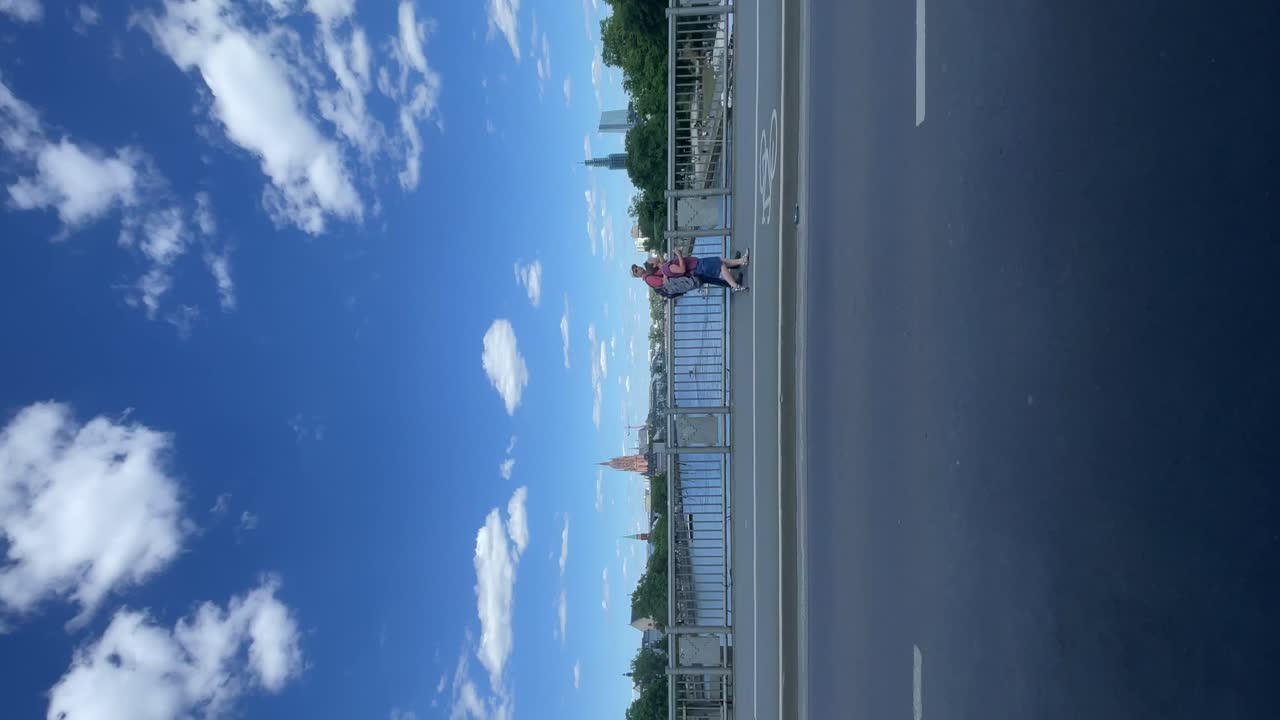 Driving Past People Walking Along Bridge In Frankfurt On Sunny Day With Blue Skies