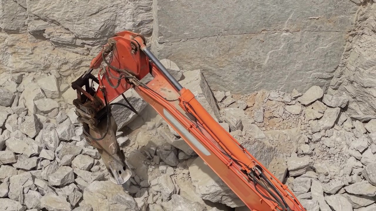 Hydraulic excavator breaking large limestone rocks