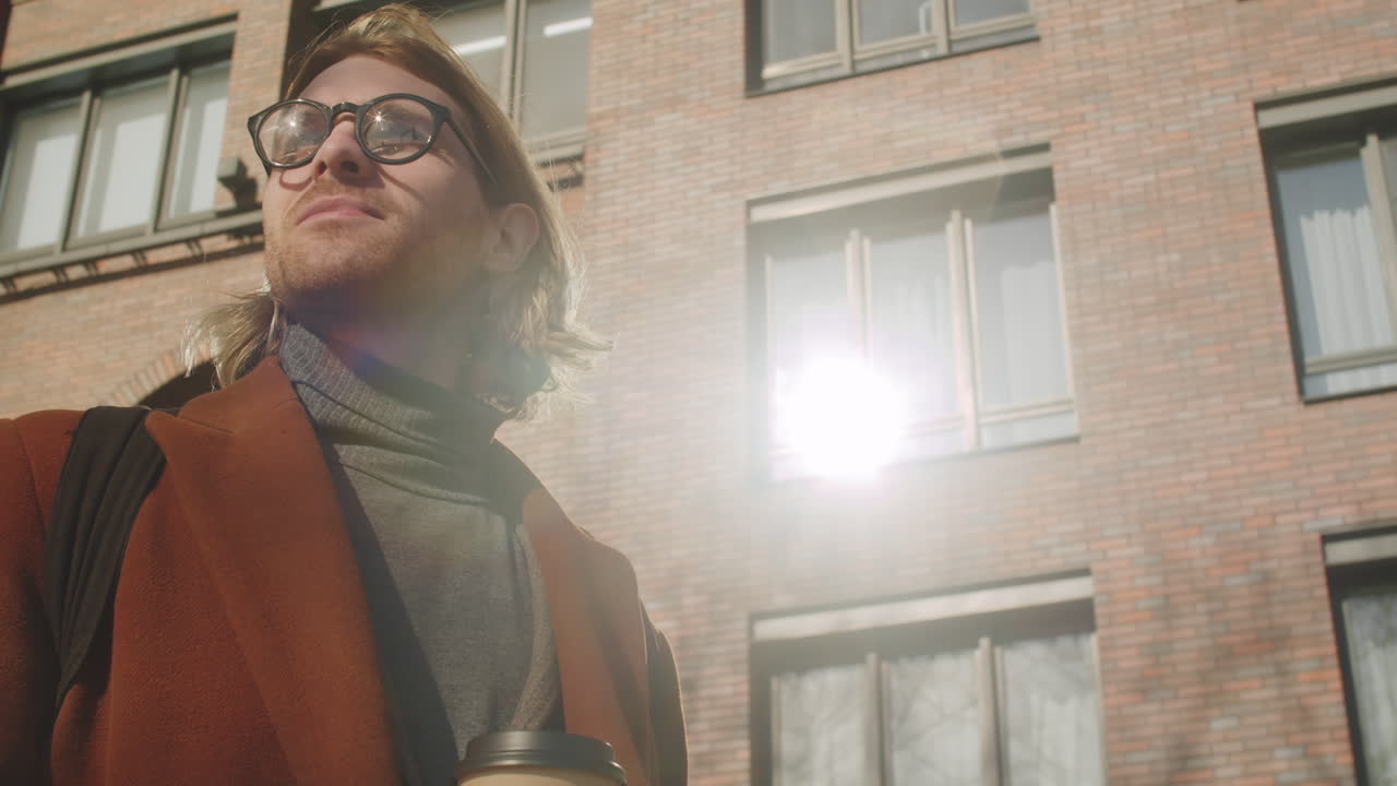 joven hombre de negocios de pie al aire libre y bebiendo para ir café