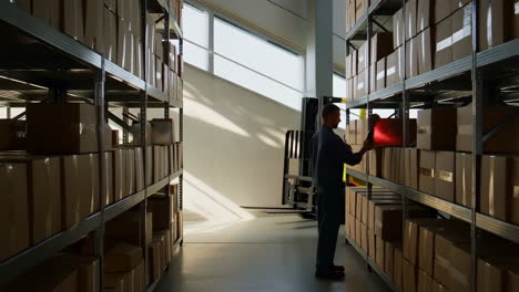 man inspecting boxes on shelves in a warehouse with a forklift
